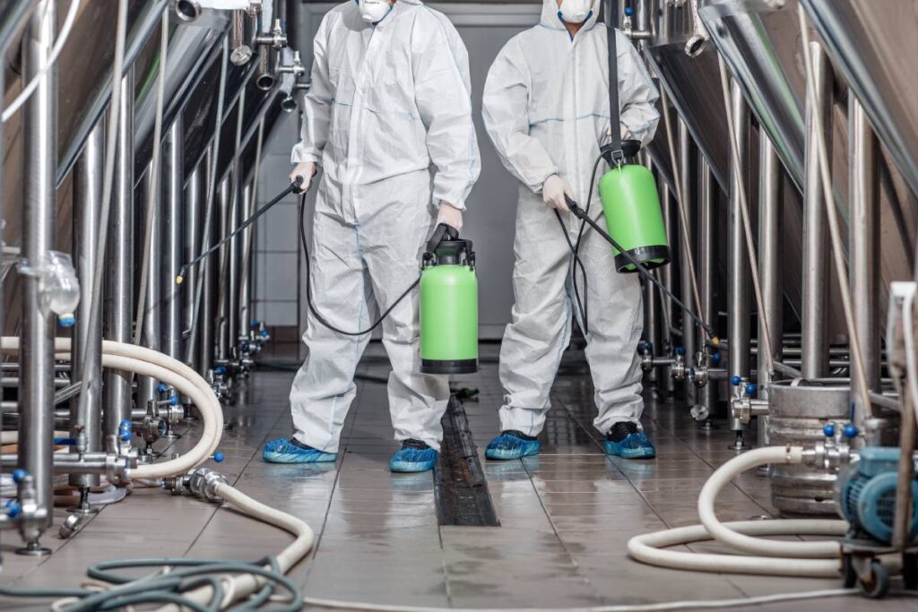 Start up, business and quarantine. Guys in protective suits and masks work at factory and Disinfected Cleaning Services