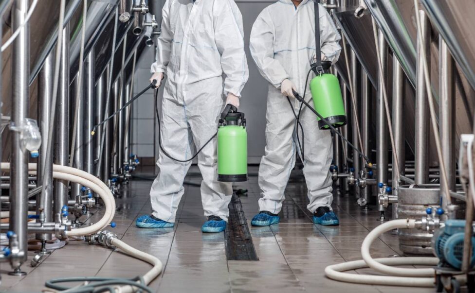 Start up, business and quarantine. Guys in protective suits and masks work at factory and Disinfected Cleaning Services