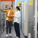 couple, satisfied customers choosing refrigerator in appliances store.