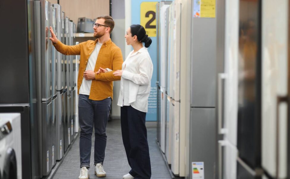 couple, satisfied customers choosing refrigerator in appliances store.
