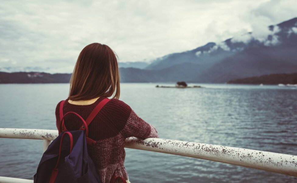 Lonely woman traveler standing absent minded and looking at the river
